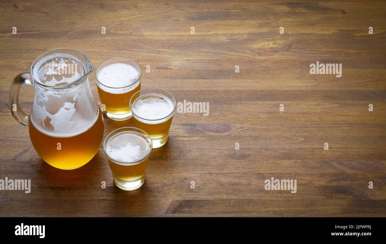 Birra in una caraffa e bicchieri in primo piano su un tavolo di legno con spazio copia Foto Stock