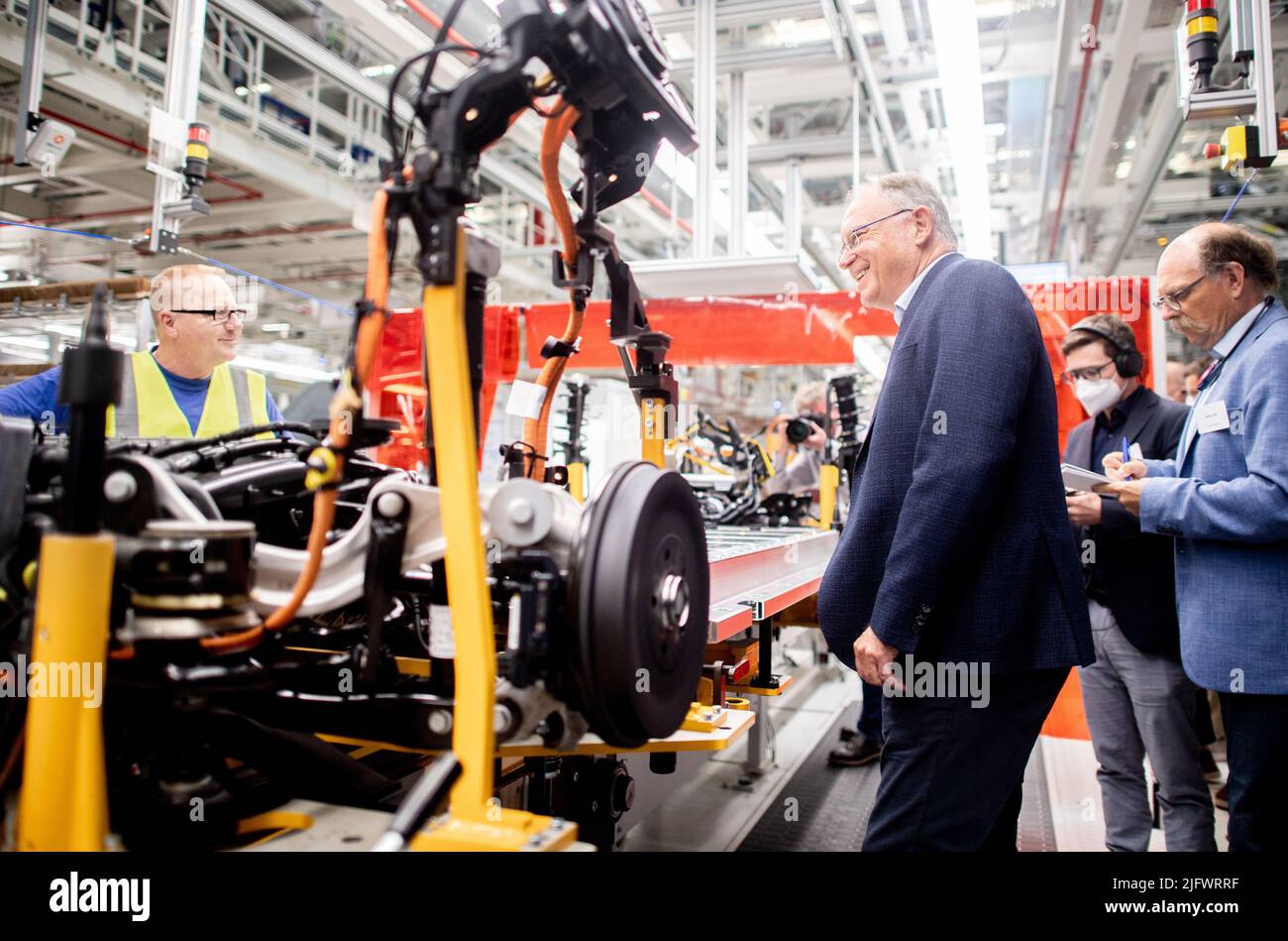 Emden, Germania. 05th luglio 2022. Stephan Weil (SPD), Ministro Presidente della bassa Sassonia, parla con un dipendente della Volkswagen in una fabbrica durante un tour della nuova linea di produzione per i veicoli Volkswagen ID.4 completamente elettrici. Il Presidente del Ministro Weil sta visitando lo stabilimento nell'ambito del suo tour estivo del 2022. Credit: Hauke-Christian Dittrich/dpa/Alamy Live News Foto Stock