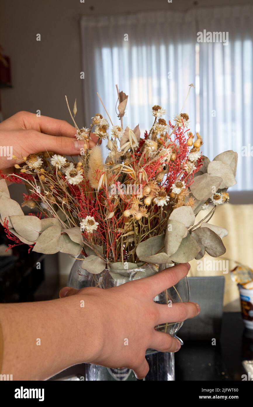 Mani di un giovane uomo bianco che arrangiano i fiori secchi di una decorazione Foto Stock