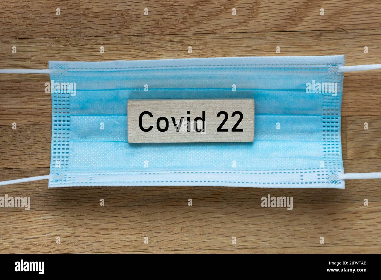Virus mask e la parola Covid 22 su un blocco di legno, concetto di diffusione di nuovi ceppi del virus BA4 e BA5 Foto Stock
