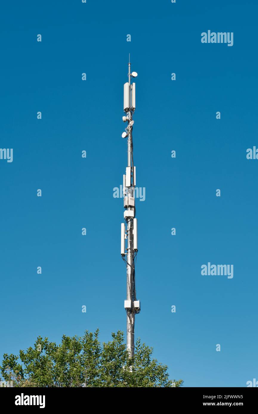 Antenna a torre per telecomunicazioni contro il cielo blu. Comunicazione wireless e moderna connessione internet mobile. Foto Stock