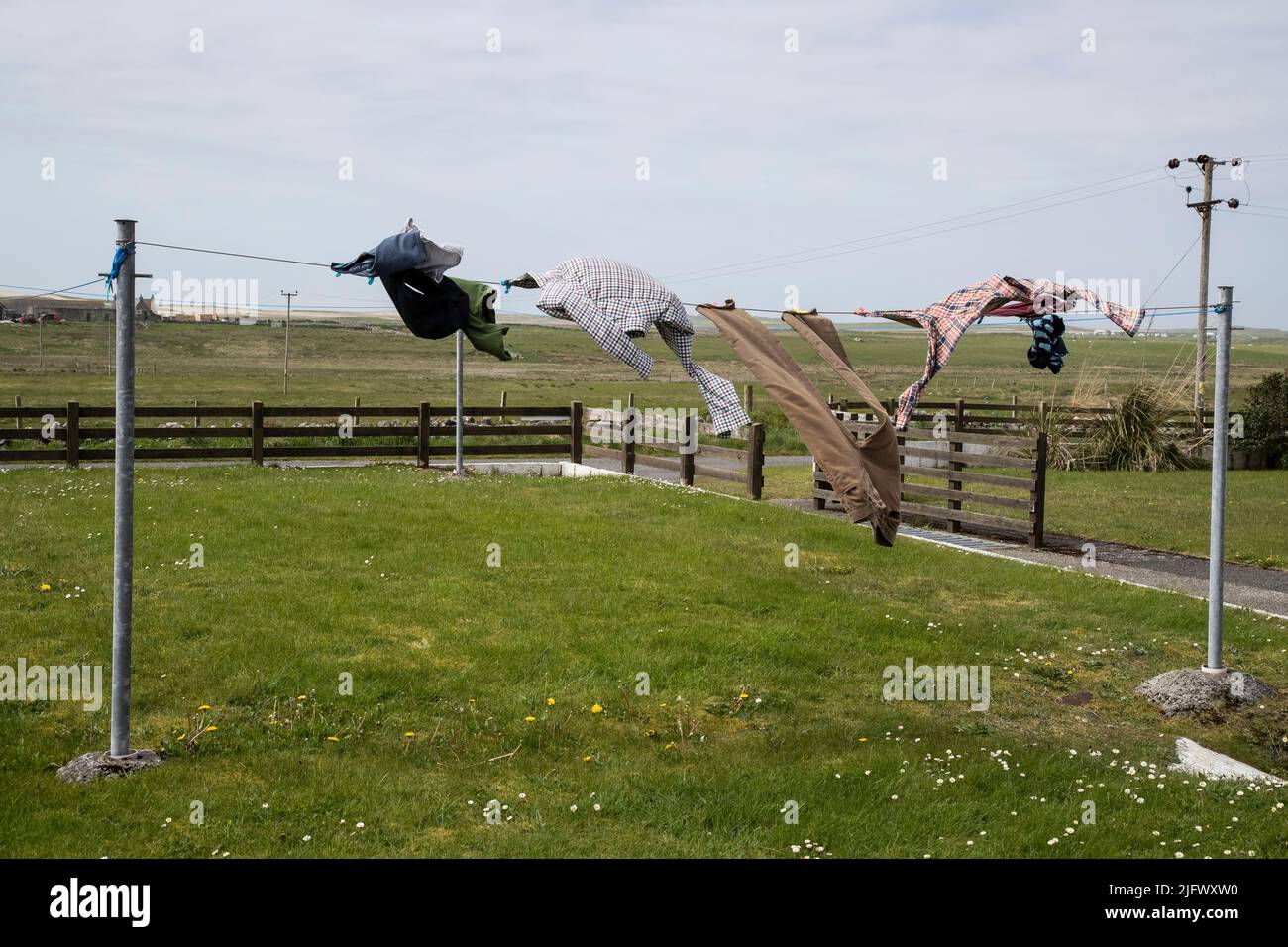 Un assortimento di vestiti che asciugano in un vento forte su una linea di lavaggio all'aperto in un giardino residenziale in Nord Uist, Scozia. Foto Stock