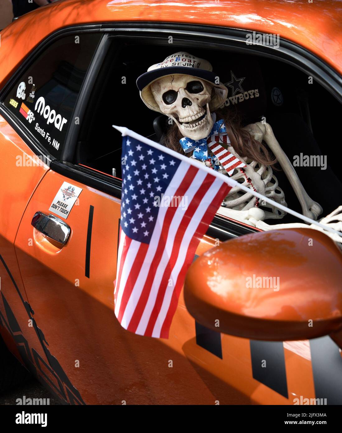 Uno scheletro di plastica di novità ospita una bandiera americana in un Dodge Challenger del 2011 in mostra in occasione di una mostra automobilistica del 4 luglio a Santa Fe, New Mexico. Foto Stock