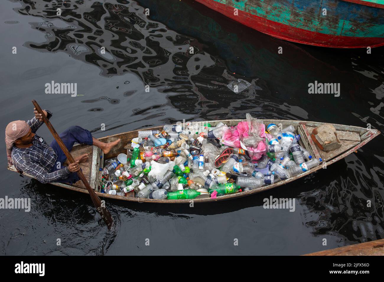 Un uomo raccoglie rifiuti di plastica dal fiume Buriganga, Dhaka, Bangladesh Foto Stock