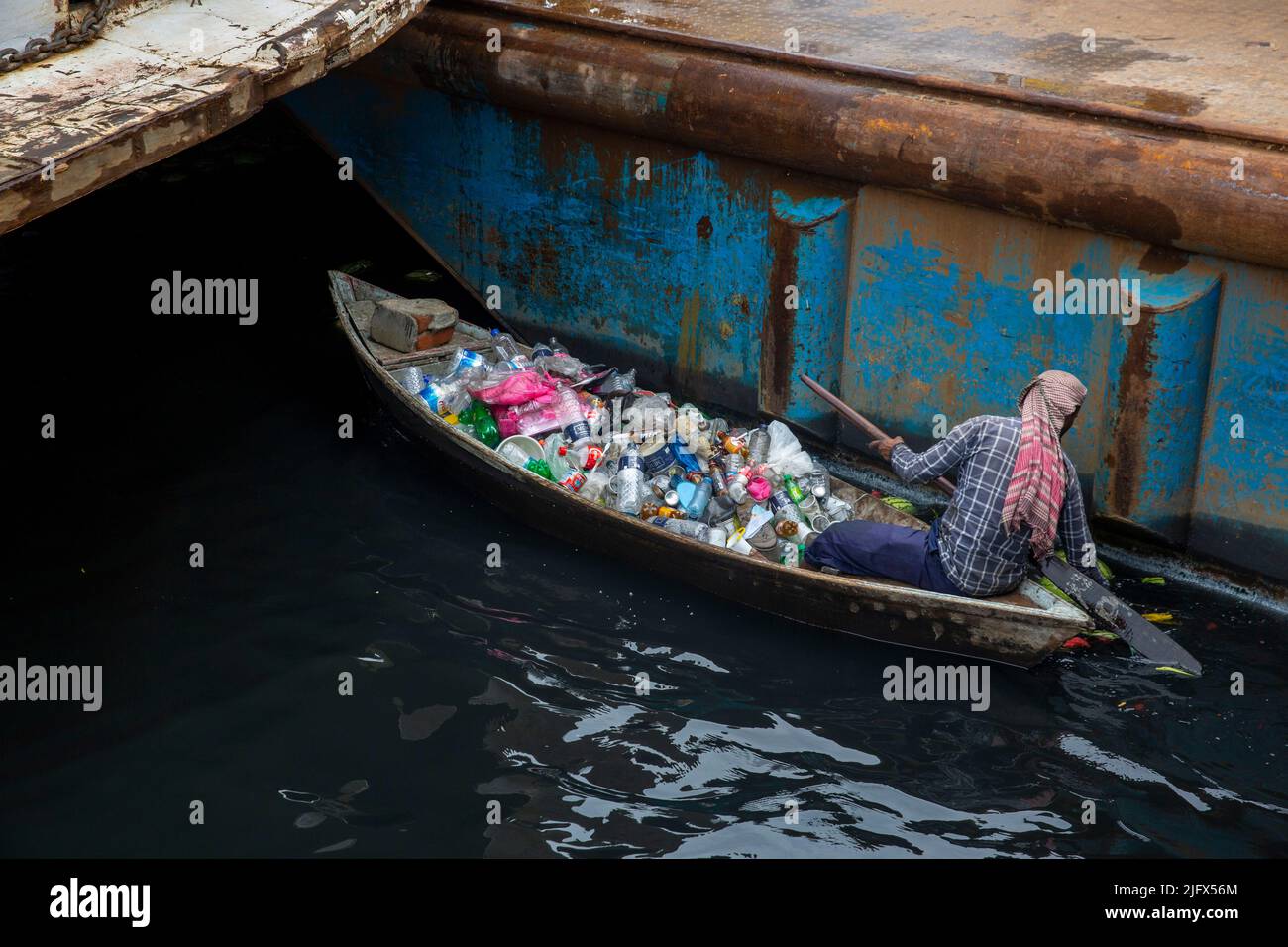 Un uomo raccoglie rifiuti di plastica dal fiume Buriganga, Dhaka, Bangladesh Foto Stock