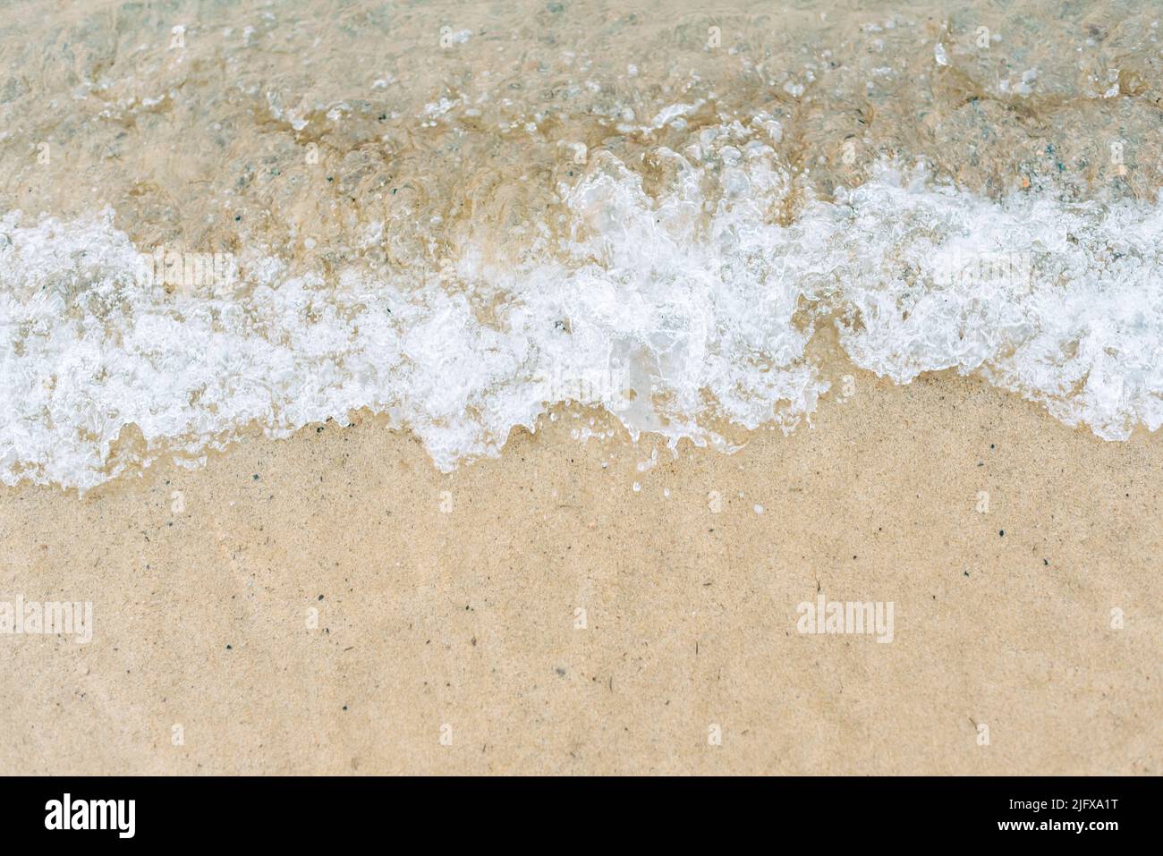 Primo piano di lavaggio delle onde sulla spiaggia di sabbia Foto Stock