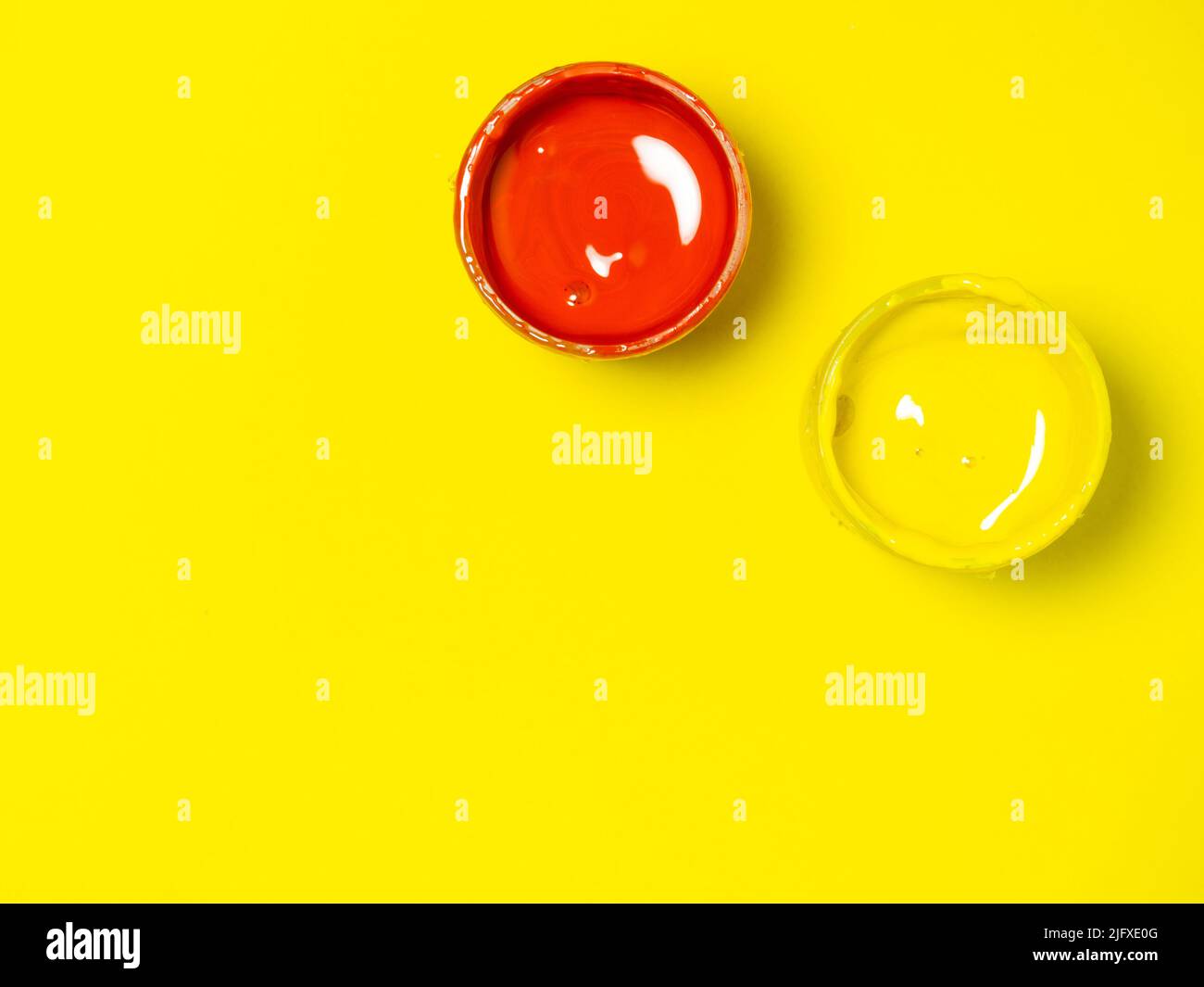 Vasetti con vernice gialla e rossa su sfondo giallo. Vasetto di gouache. Sfondo luminoso. Background creativo. Laboratorio dell'artista. Foto Stock