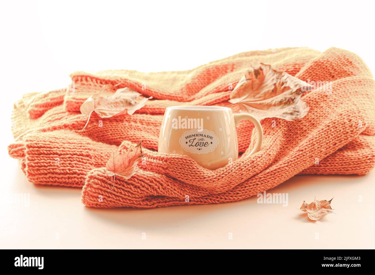 Composizione autunnale. Maglione a maglia arancione con una tazza di tè e foglie d'autunno Foto Stock
