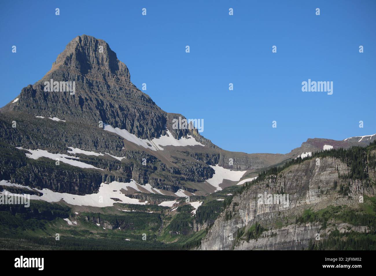 Glacier National Park Montana USA - Logan Pass, Road to the Sun, cielo blu brillante sulla maestosa vetta del Monte Reynolds con cascate di neve sciolte Foto Stock