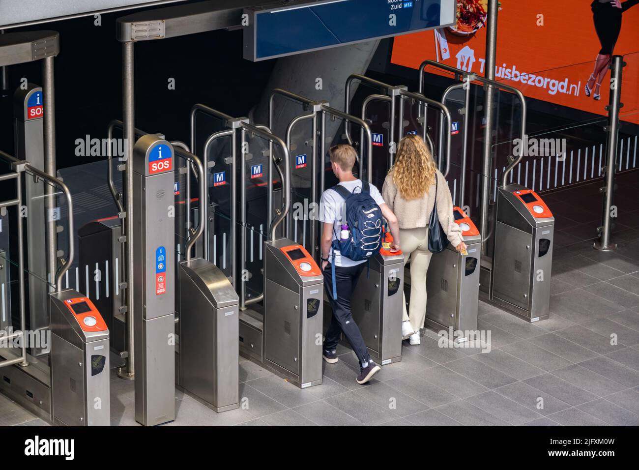 Amsterdam, Paesi Bassi - 21 giugno 2022: Due giovani che entrano nella stazione della metropolitana e nelle tariffe di scansione Foto Stock