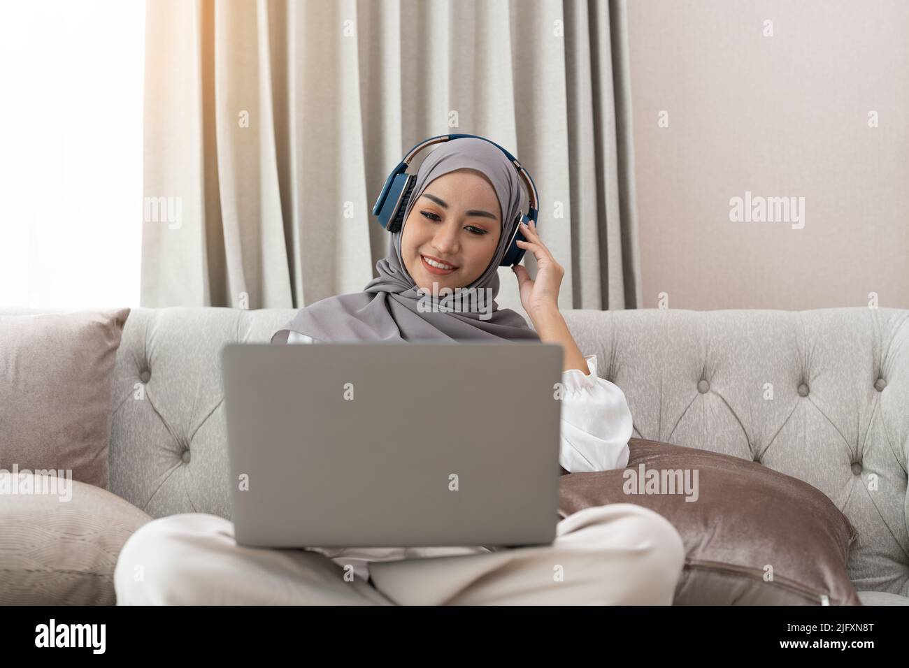 Donna musulmana asiatica che ha videoconferenza sul suo laptop a casa, apprendimento online o concetto di lavoro da casa Foto Stock