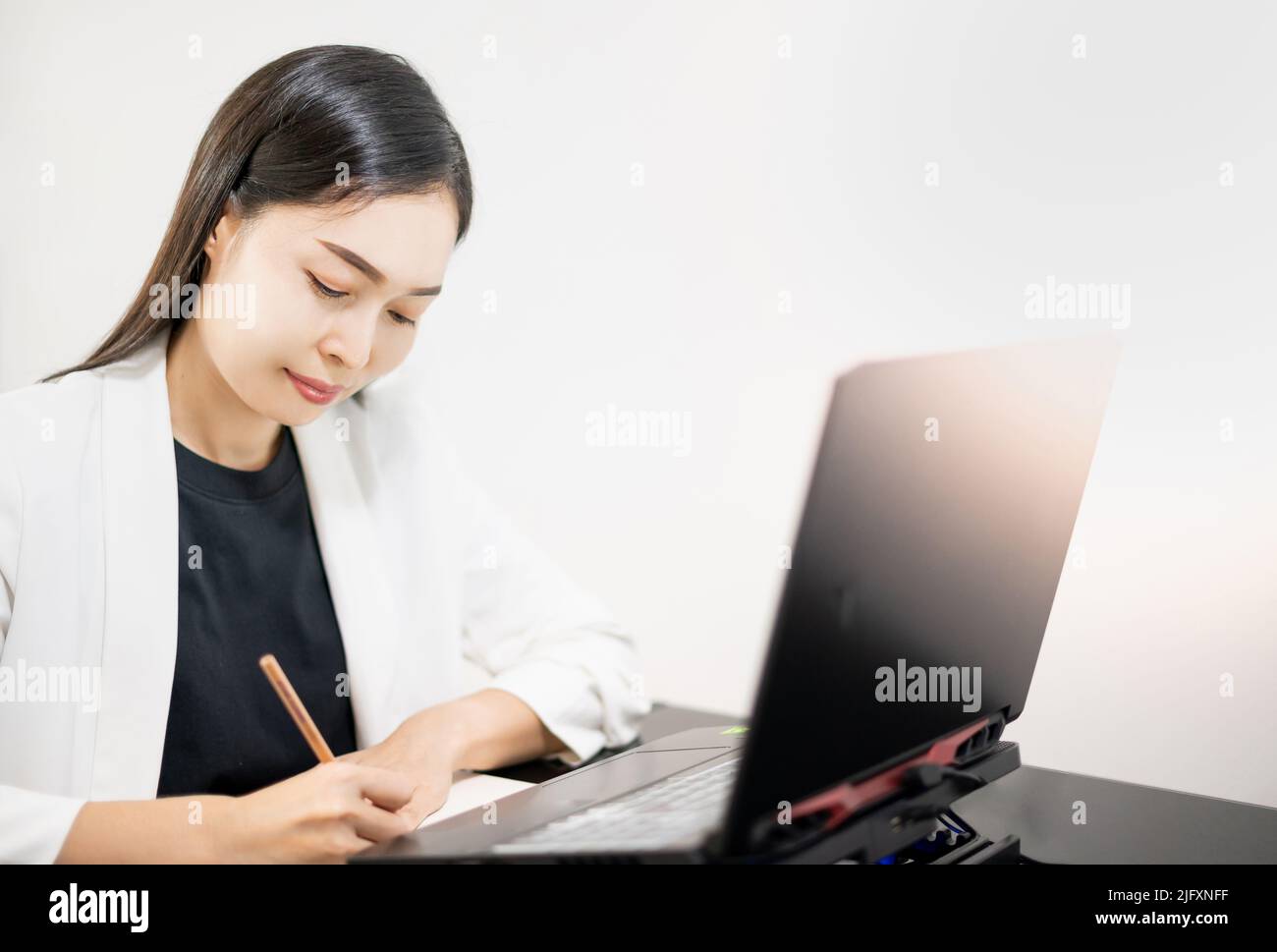 La donna d'affari asiatica indossa casualmente un computer portatile mentre lavora nel soggiorno di casa. Business online, giovane professionista sul posto di lavoro. Lavorare da casa. Foto Stock