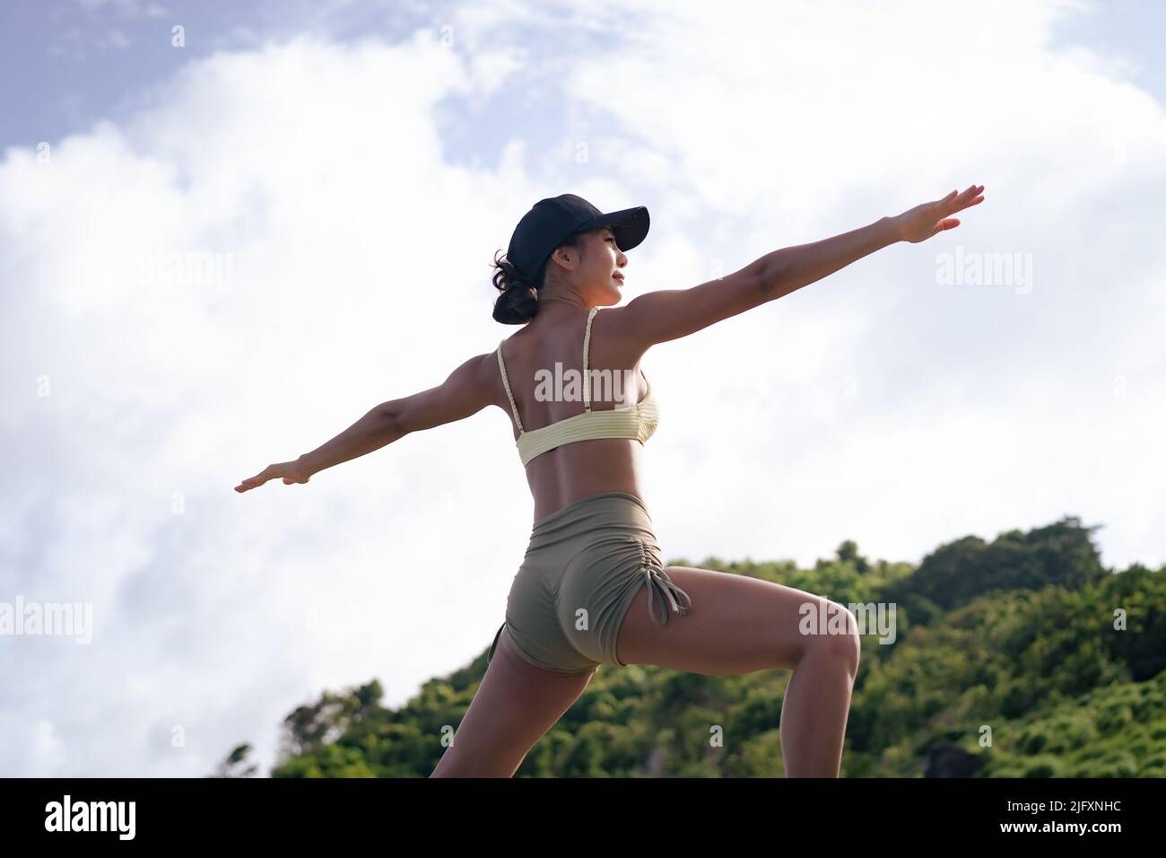 Giovane donna asiatica che pratica yoga sulla cima della montagna. Bella femmina che si allenano all'aperto nella natura Foto Stock