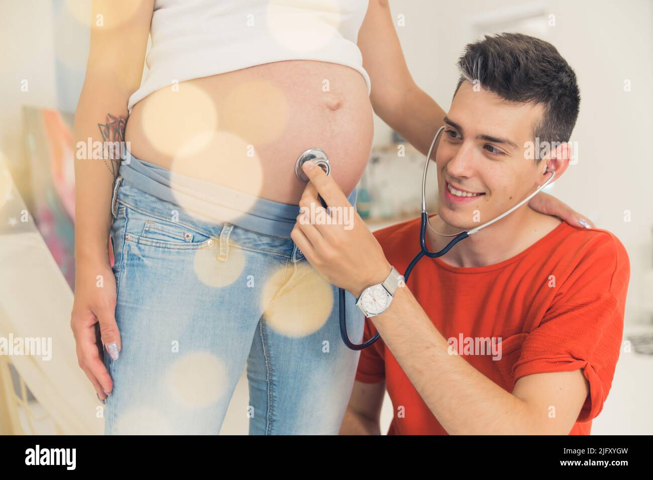 marito che usa uno stetoscopio per ascoltare il suono del bambino nel ventre della moglie incinta. Foto di alta qualità Foto Stock