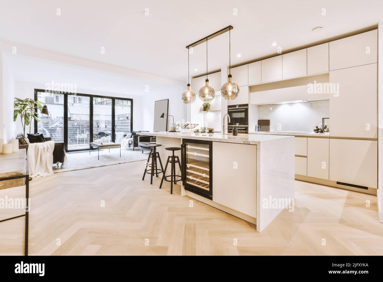 Mobili bianchi con bancone in legno di cucina moderna e tavolo da pranzo nel soggiorno dell'appartamento Foto Stock