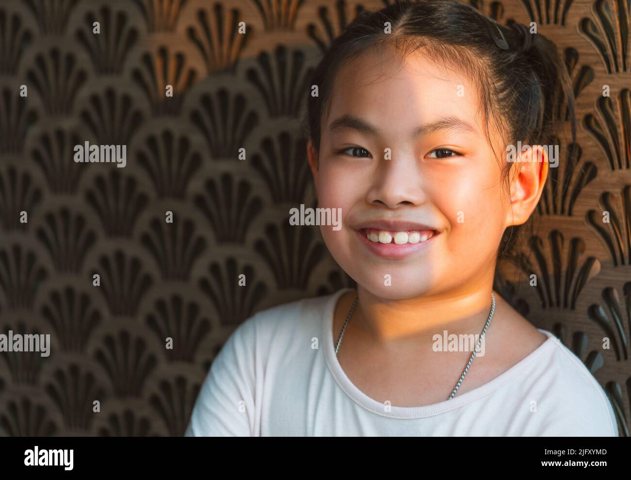 Ritratto di ragazza bambino asiatica carina con bella parete di legno marrone, viso sorridente, luce naturale del sole, primo piano immagine di ragazza bambino sano, spazio vuoto Foto Stock
