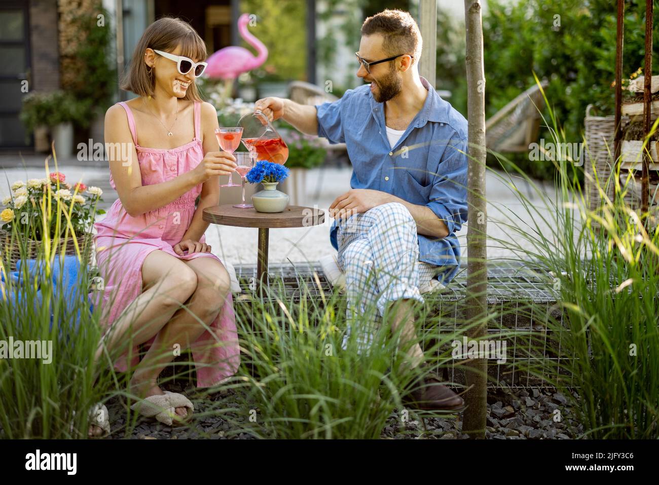 Le coppie alla moda hanno un drink nel loro cortile Foto Stock