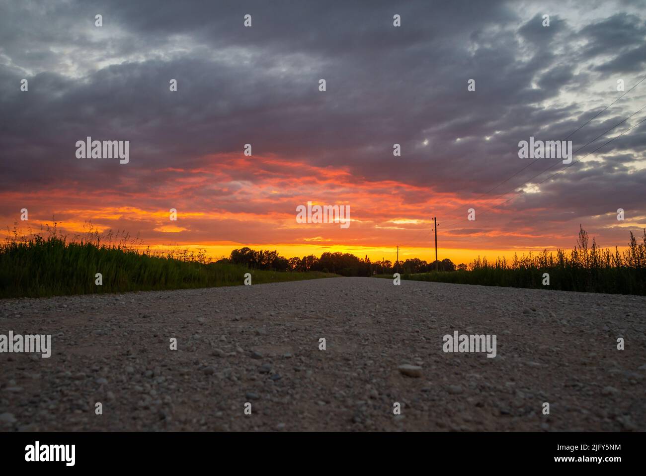 Paesaggio rurale paesaggistico con strada sterrata rurale rotto al tramonto. Foto Stock