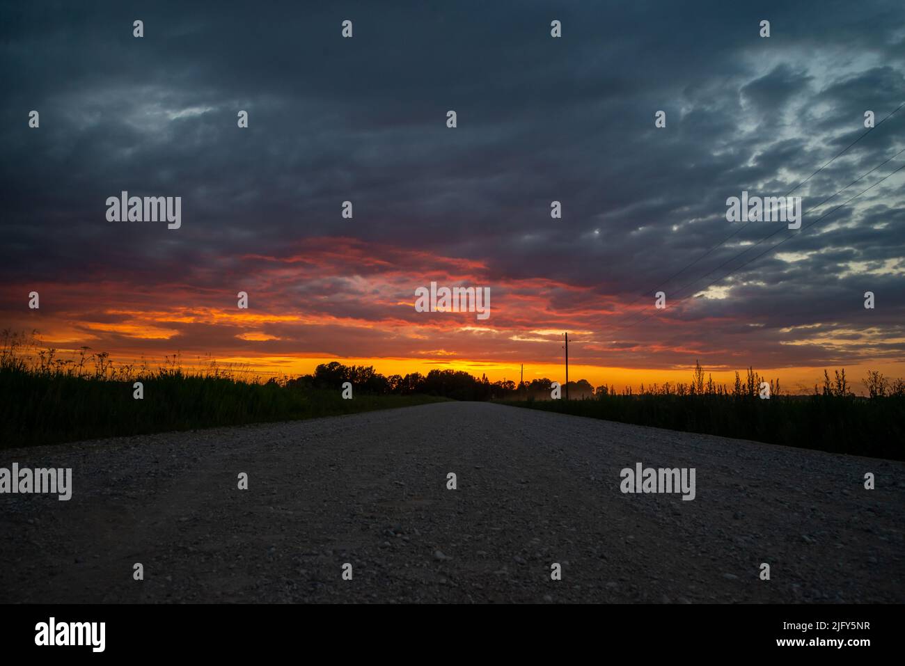 Paesaggio rurale paesaggistico con strada sterrata rurale rotto al tramonto. Foto Stock