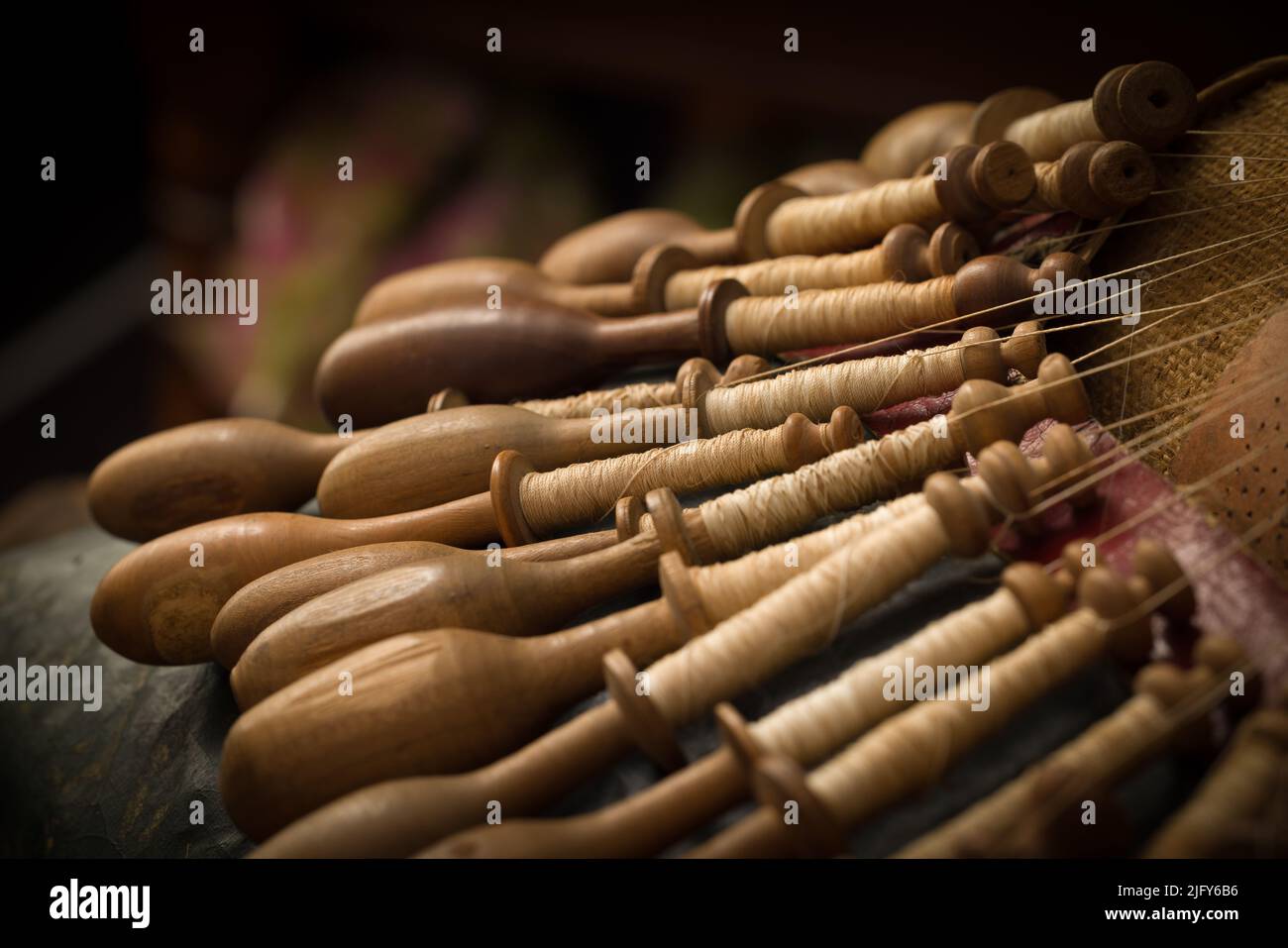 Vista ravvicinata su un pizzo fiammingo antico che fa il cuscino con le rocche di legno molto vecchie Foto Stock