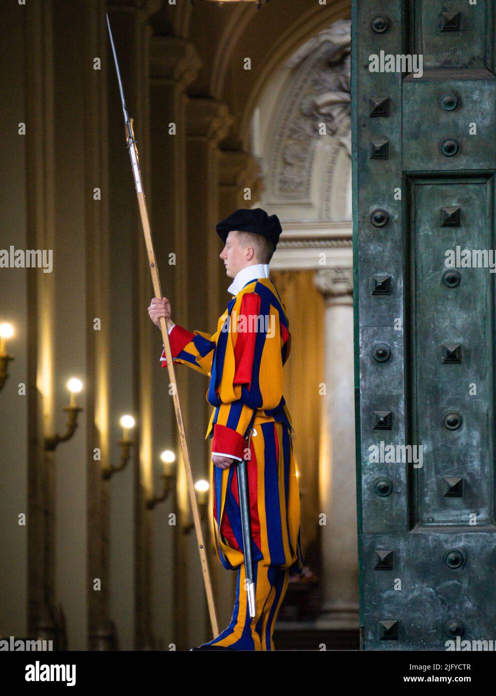 Città del Vaticano, Marzo 2022. Immagine ravvicinata di uno svizzero papale vestito in uniforme tradizionale, che custodisce la porta di ferro. Foto Stock