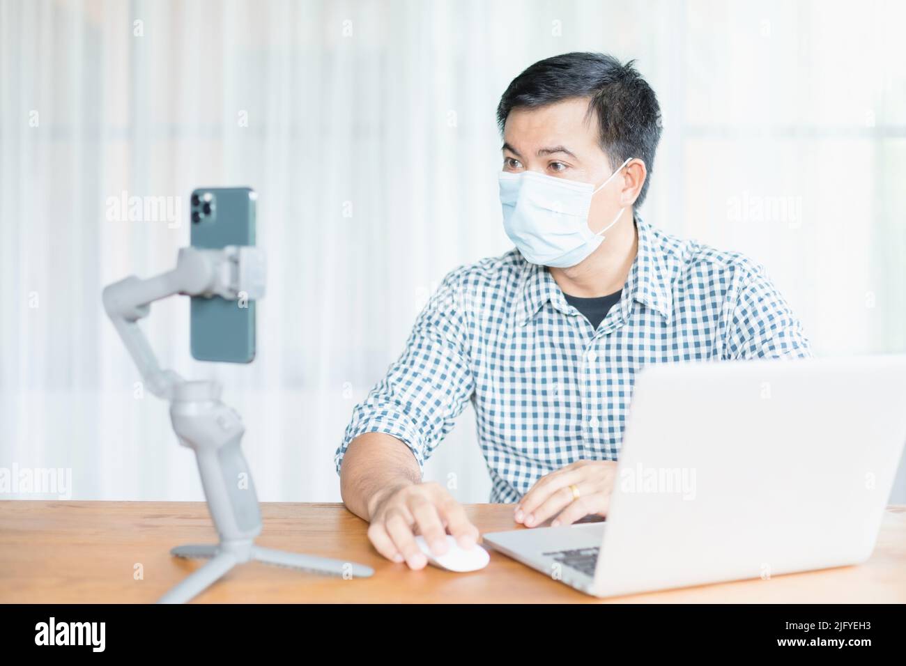 Uomo asiatico indossare maschera preventiva e lavorare da casa in situazione di malattia di Corona Virus (COVID-19). Lavora da casa e concetto sano Foto Stock