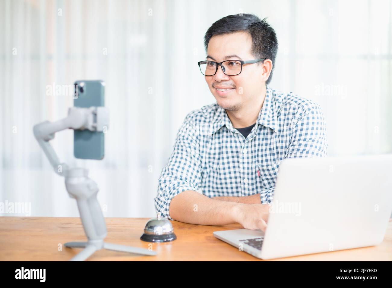 Uomo asiatico che cerca di smartphone per comunicare mentre lavora a casa in situazione di Corona Virus Disease (COVID-19). Lavoro da casa e sano conce Foto Stock