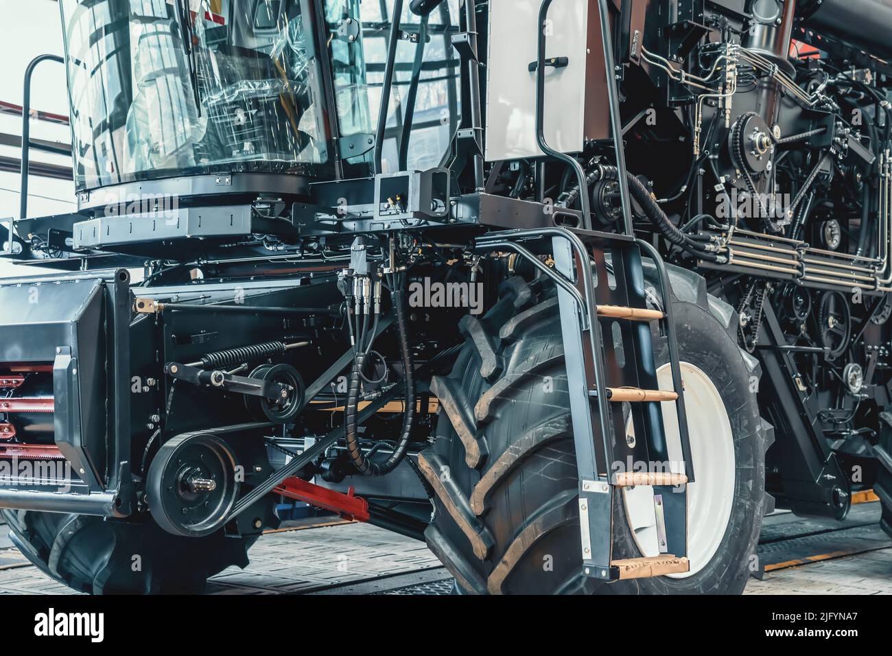 Mietitrebbia o trattore moderni su una linea di produzione di stabilimenti o fabbriche di assemblaggio. Macchine industriali agricole. Foto Stock
