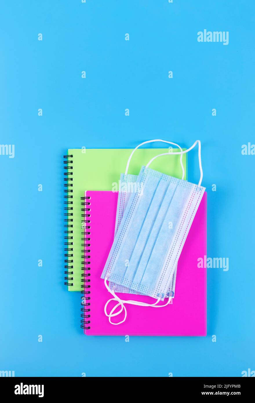 Due copybook a spirale con maschere facciali su sfondo blu. Vista dall'alto. Nuovo concetto normale. Foto Stock