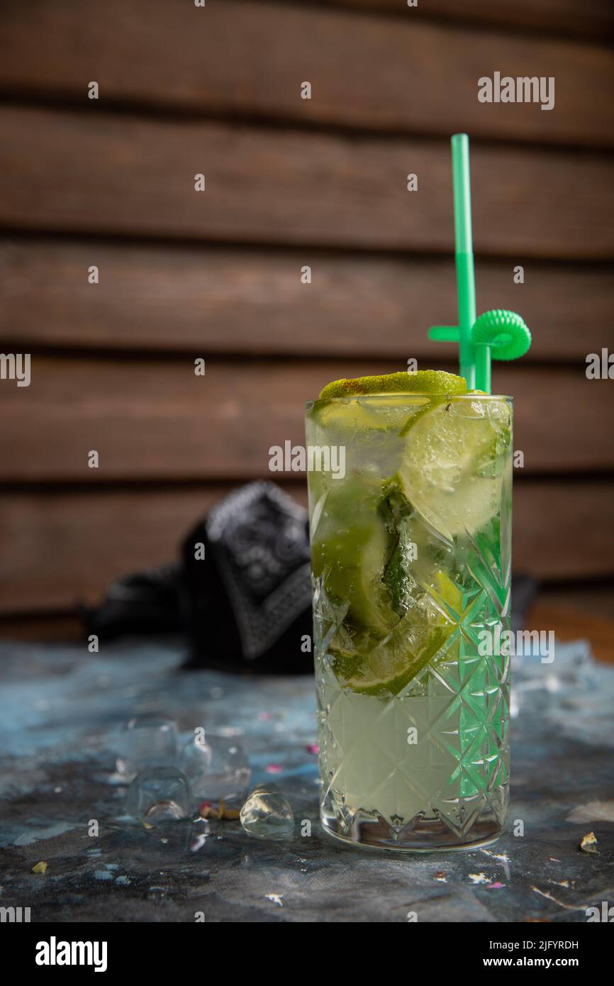 Un colpo verticale di un vetro di mojito con una paglia verde su un tavolo di marmo grigio Foto Stock