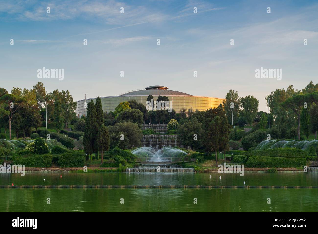EUR lago a Roma, Italia. Tramonto nel parco con il Palazzo dello Sport e fontane colorate Foto Stock