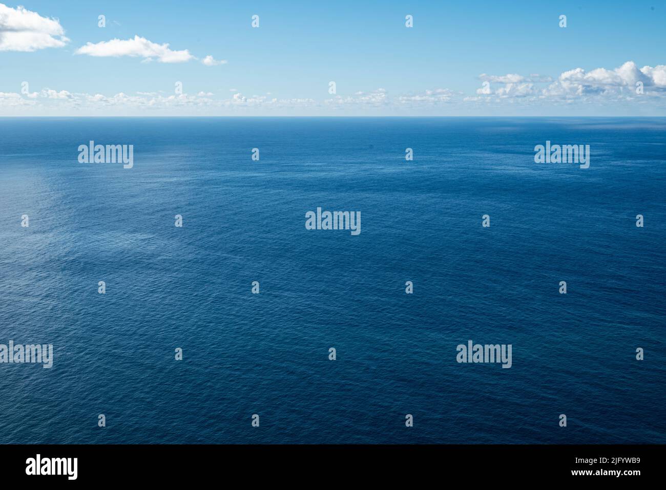 Mare panoramico limpido e minimalista che mostra le infinite acque blu dell'Oceano Atlantico sulla costa di Madeira sotto un cielo blu soleggiato Foto Stock