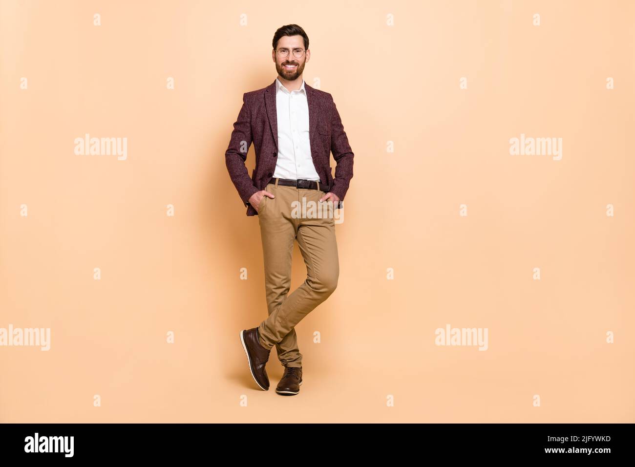 Immagine a grandezza naturale di giovane uomo d'affari bello e bello tenere le mani in tasche isolato su sfondo di colore beige Foto Stock