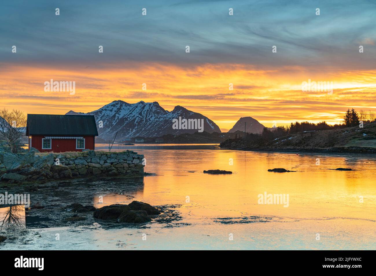 Montagne innevate e cabina rossa dei pescatori sotto il cielo all'alba, Ballstad, Vestvagoy, Isole Lofoten, Norvegia, Scandinavia, Europa Foto Stock