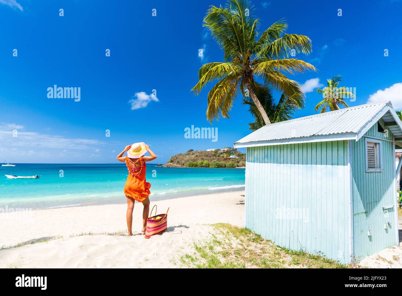 Bella donna con cappello di paglia e vestito rilassante sulla spiaggia tropicale, Antigua, Isole Leeward, West Indies, Caraibi, America Centrale Foto Stock