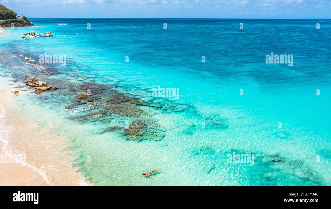 Donna galleggiante nel mare cristallino su idilliaca spiaggia tropicale, vista dall'alto, Antigua, Isole Leeward, Indie Occidentali, Caraibi, America Centrale Foto Stock