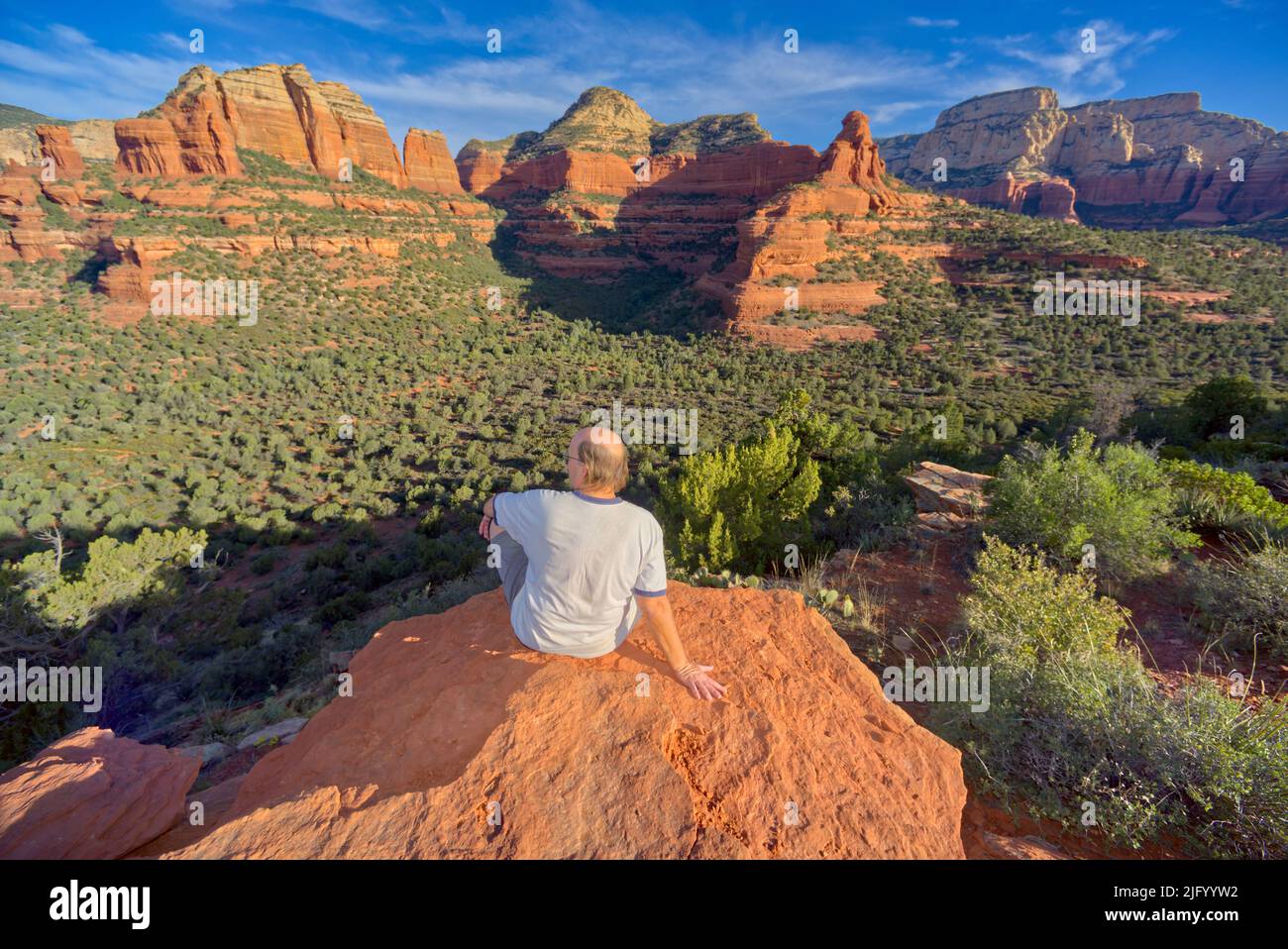 Un uomo seduto sulla cima della montagna di Mescal che domina Deadmans Pass a Sedona, Arizona, Stati Uniti d'America, Nord America Foto Stock