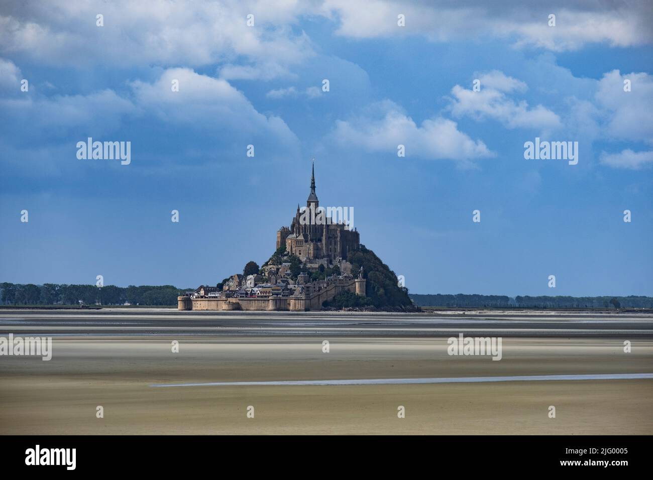 Le Mont Saint Michel, patrimonio dell'umanità dell'UNESCO, in bassa marea in una giornata di sole con alcune nuvole bianche, Normandia, Francia, Europa Foto Stock