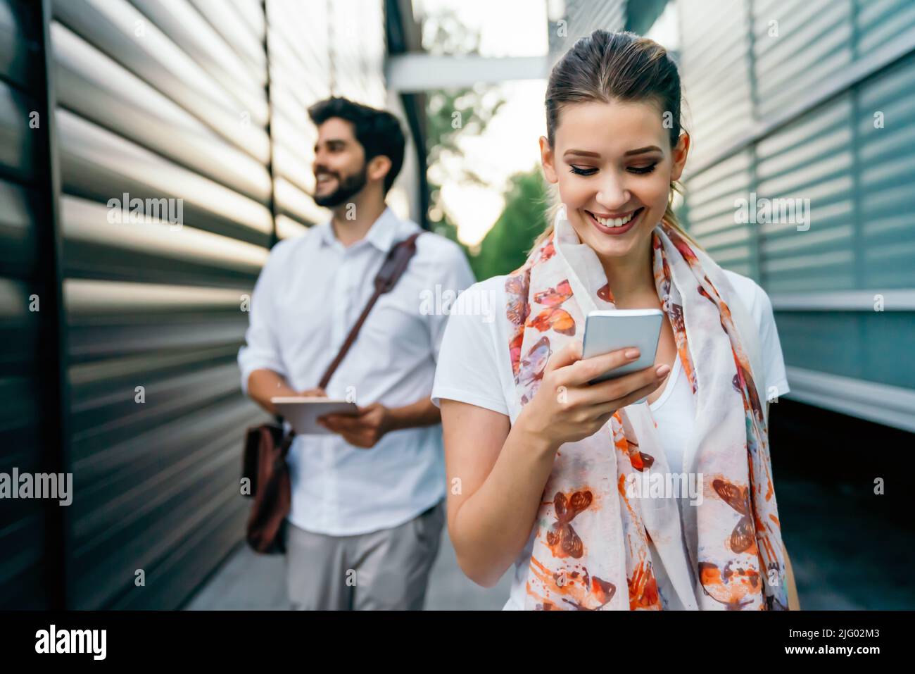 Felici le persone che lavorano all'aperto con i dispositivi digitali. Tecnologia aziendale smartphone, tablet Foto Stock