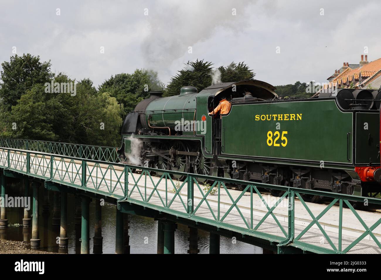 Treno a vapore (locomotiva classe SR S15) che traina carrozze passeggeri rosse attraverso il fiume Esk, North Yorkshire, Regno Unito Foto Stock