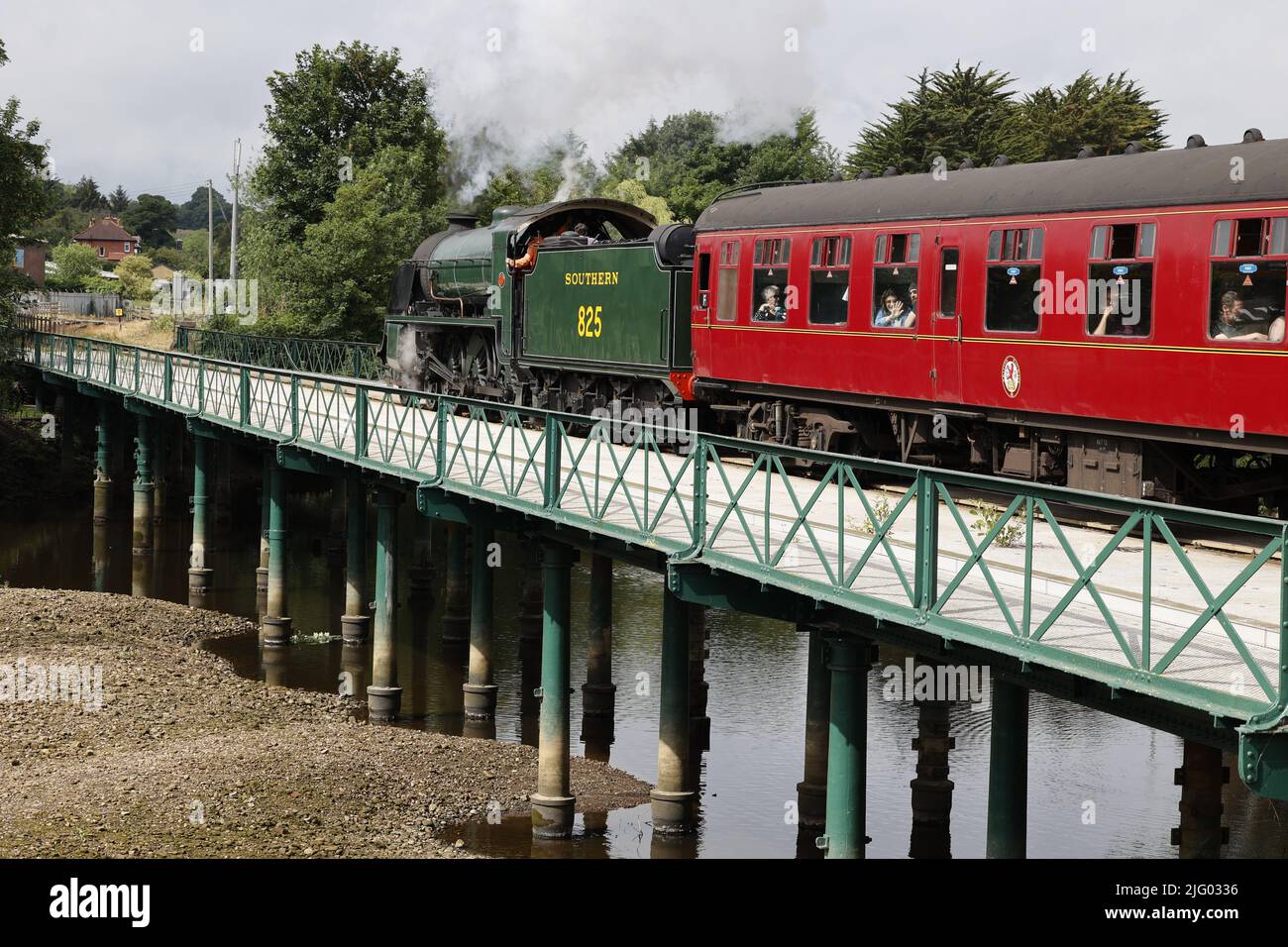 Treno a vapore (locomotiva classe SR S15) che traina carrozze passeggeri rosse attraverso il fiume Esk, North Yorkshire, Regno Unito Foto Stock