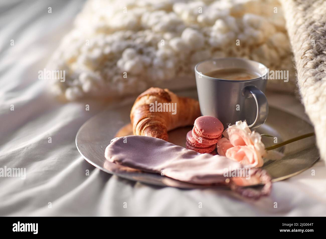 croissant, caffè e maschera per gli occhi a letto Foto Stock