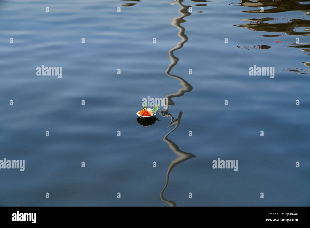 Primo piano che mostra i riflessi di lampade e fiori che galleggiano come un'offerta agli antenati nelle acque del fiume santo Godavari, Nasik, Maharashtra, India Foto Stock