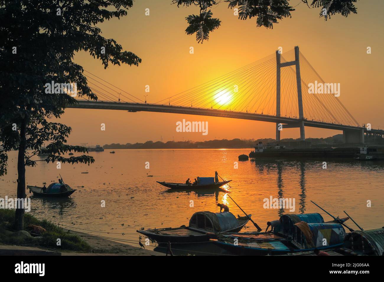 Kolkata, 20,Marzo,2013; Vista panoramica di Vidyasagar Setu, ponte con cornice riflesso del sole e barche locali nel fiume Hooghly Kolkata, Bengala Occidentale. Foto Stock