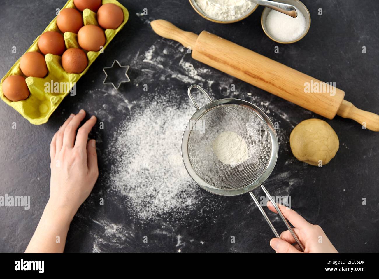mani con setacciatore setacciare la farina sul tavolo da cucina Foto Stock