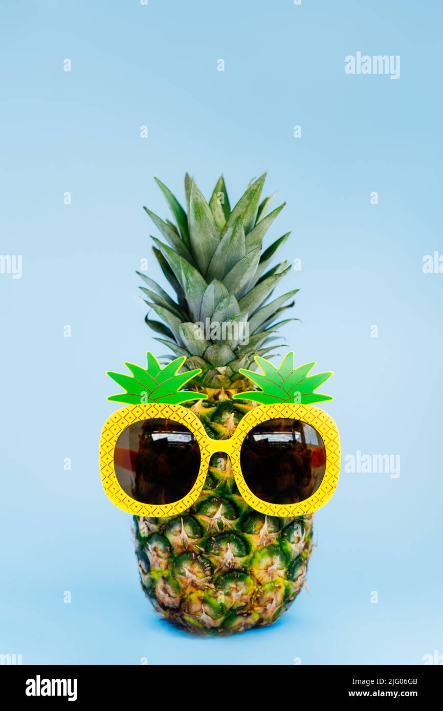 Ananas divertente in un bicchiere di ananas a forma di sfondo verticale blu. Estate in stile tropicale sull'atmosfera della spiaggia. Frutta esotica. Resort vacat Foto Stock
