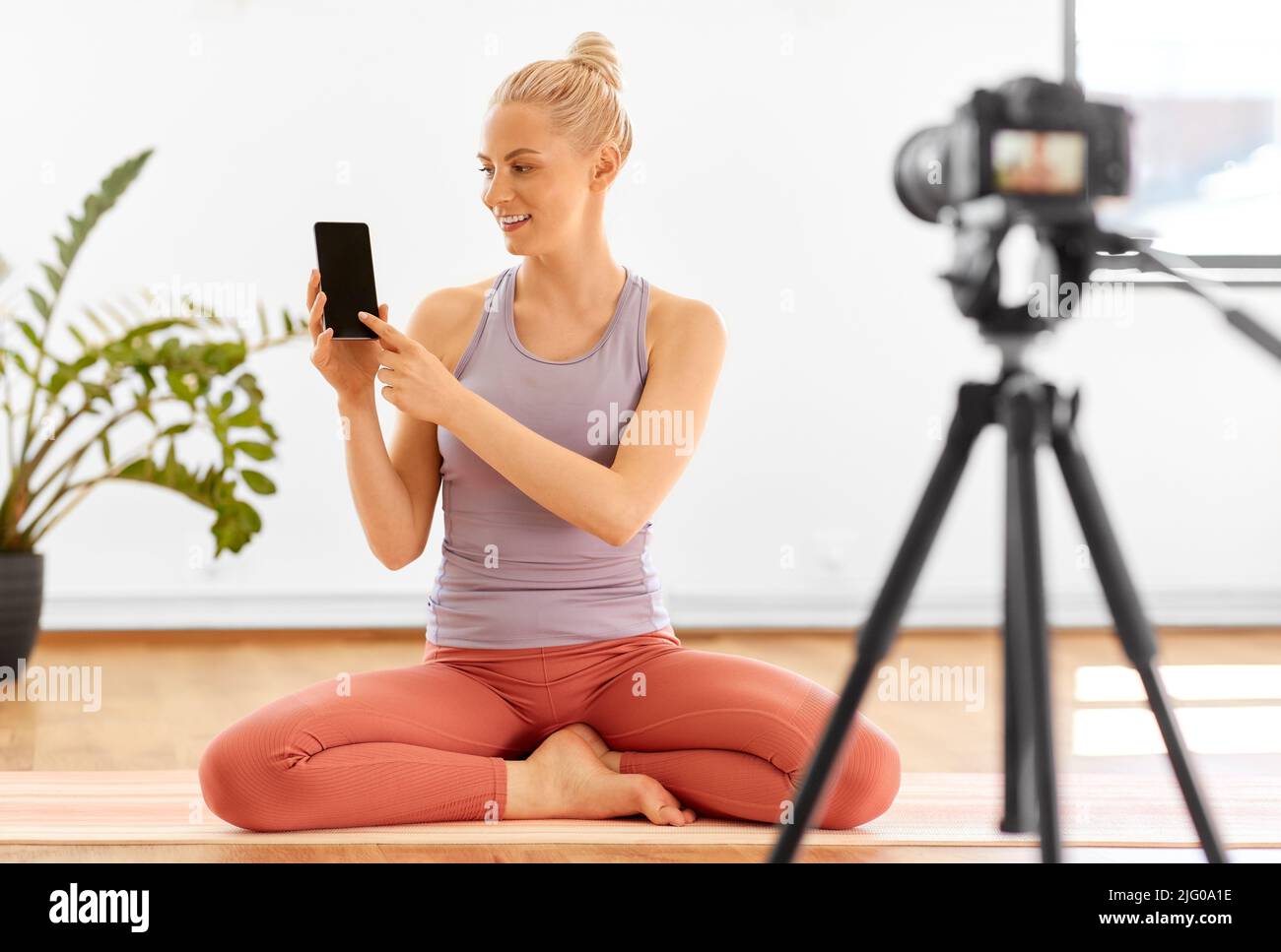 donna con il telefono in streaming per il blog yoga a casa Foto Stock