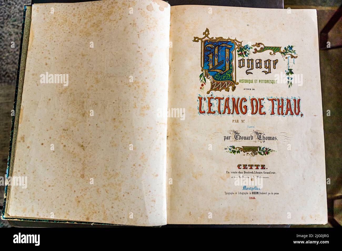 La pagina del titolo aperta di un libro storico al Domaine Tarbouriech vicino a Marseillan, Hérault, Francia, recita "Voyage historique et pittoresque autour de l'Étang de Thau" di Edouard Thomas, stampato nel 1846 a Cette – oggi Sète – e Montpellier. L'opera antiquaria descrive la storia e il paesaggio intorno all'Étang de Thau già nel XIX secolo. Foto Stock