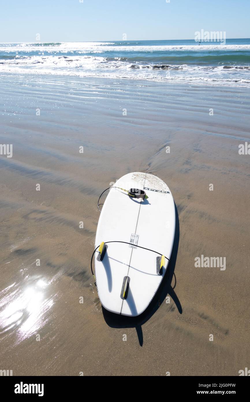 Lone Surfboard su sabbia bagnata con mare sullo sfondo Huntington Beach California meridionale USA Foto Stock