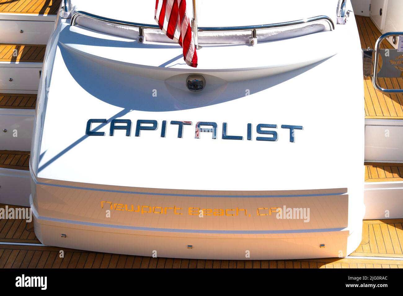 Stern di un lussuoso yacht a motore chiamato capitalista, sul personale di poppa indossato gli Stati Uniti Ensign una grande stella e strisce bandiera americana, Newport Beach USA Foto Stock